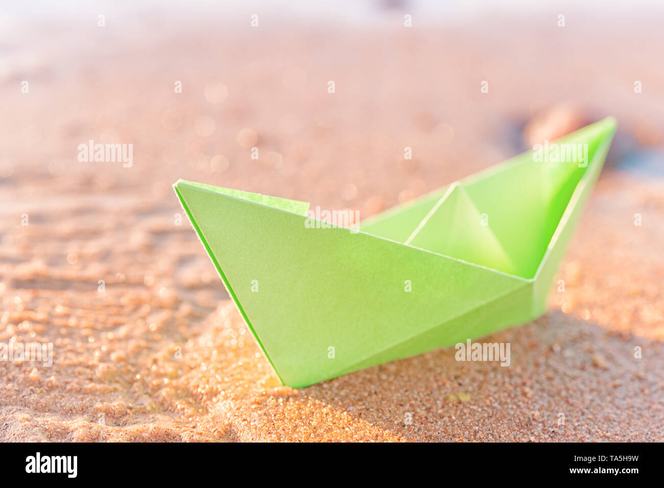 Libro verde barca sulla spiaggia di sabbia all'esterno. Il fuoco selettivo sulla barca Foto Stock