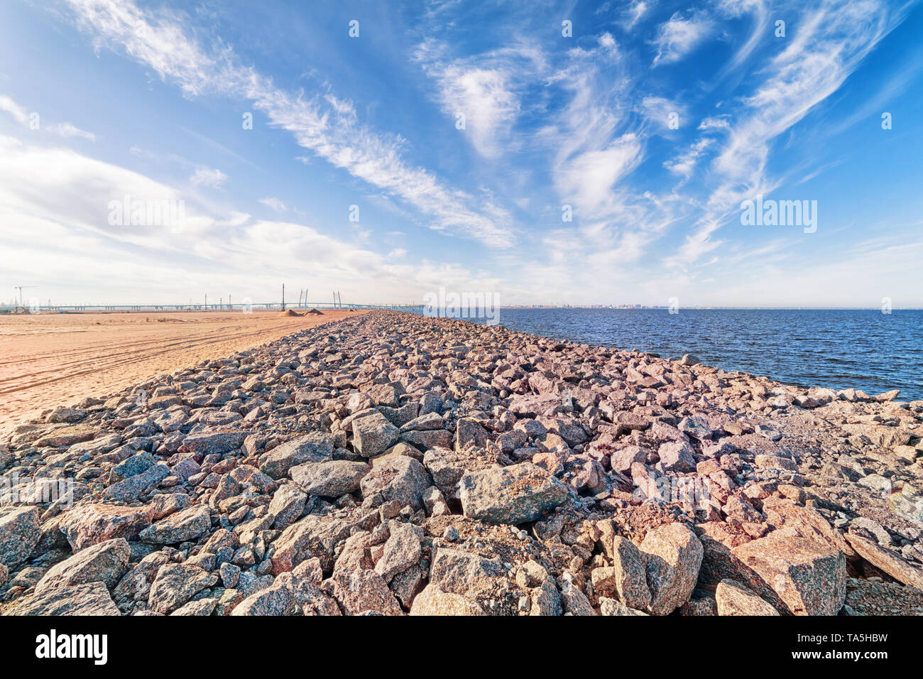 Ampio angolo di mare paesaggio industriale con skyline, sabbia, sky pietre e ponte distanti a San Pietroburgo, Russia Foto Stock