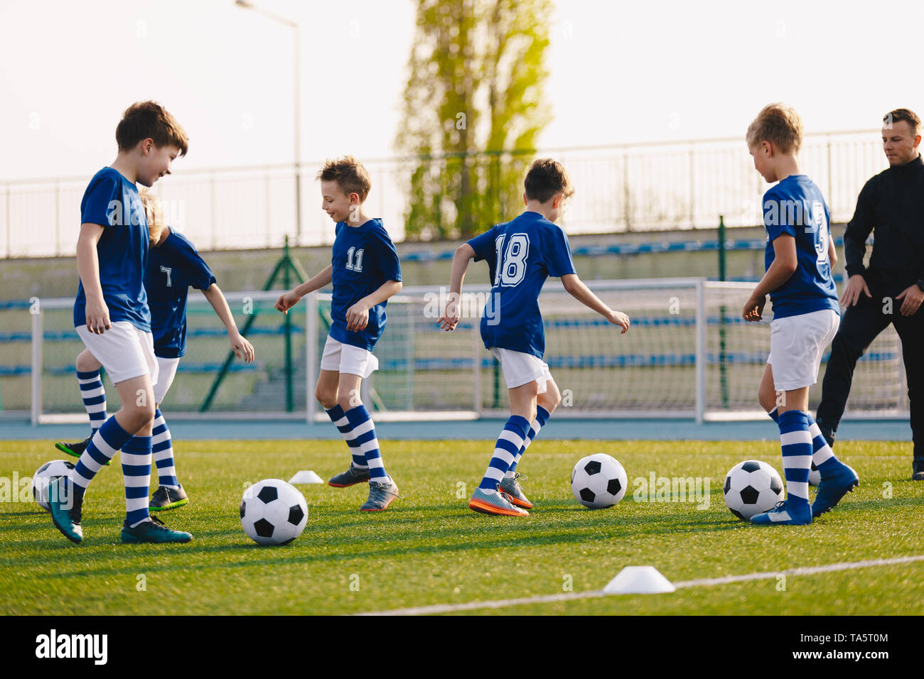 I ragazzi in Sport Club sul calcio della formazione. I bambini migliorano le abilità di calcio in erba naturale Campo in Erba. Il calcio sessione di pratica per i bambini Foto Stock