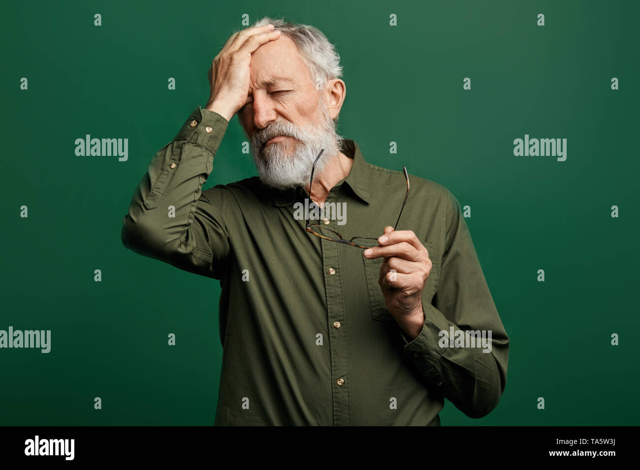 Triste premuto l'uomo ha un mal di testa e si toglie gli occhiali e toccando il suo fronte. l uomo ha la pressione arteriosa alta. vecchio uomo ha molti problemi Foto Stock