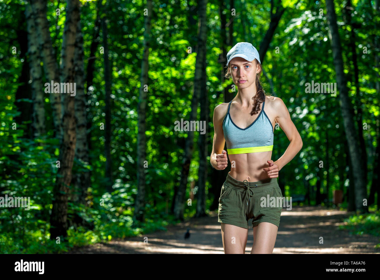 Ritratto di un bellissimo sportive muscolare durante il jogging in un parco di estate Foto Stock