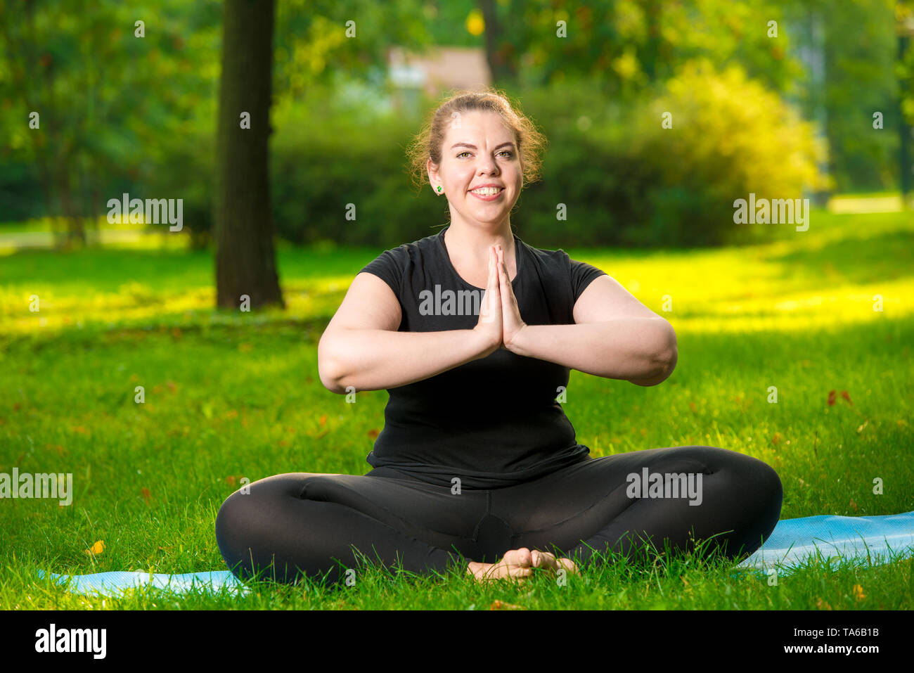 Taglie donna in posa di park di eseguire esercizi in lotus pongono Foto Stock