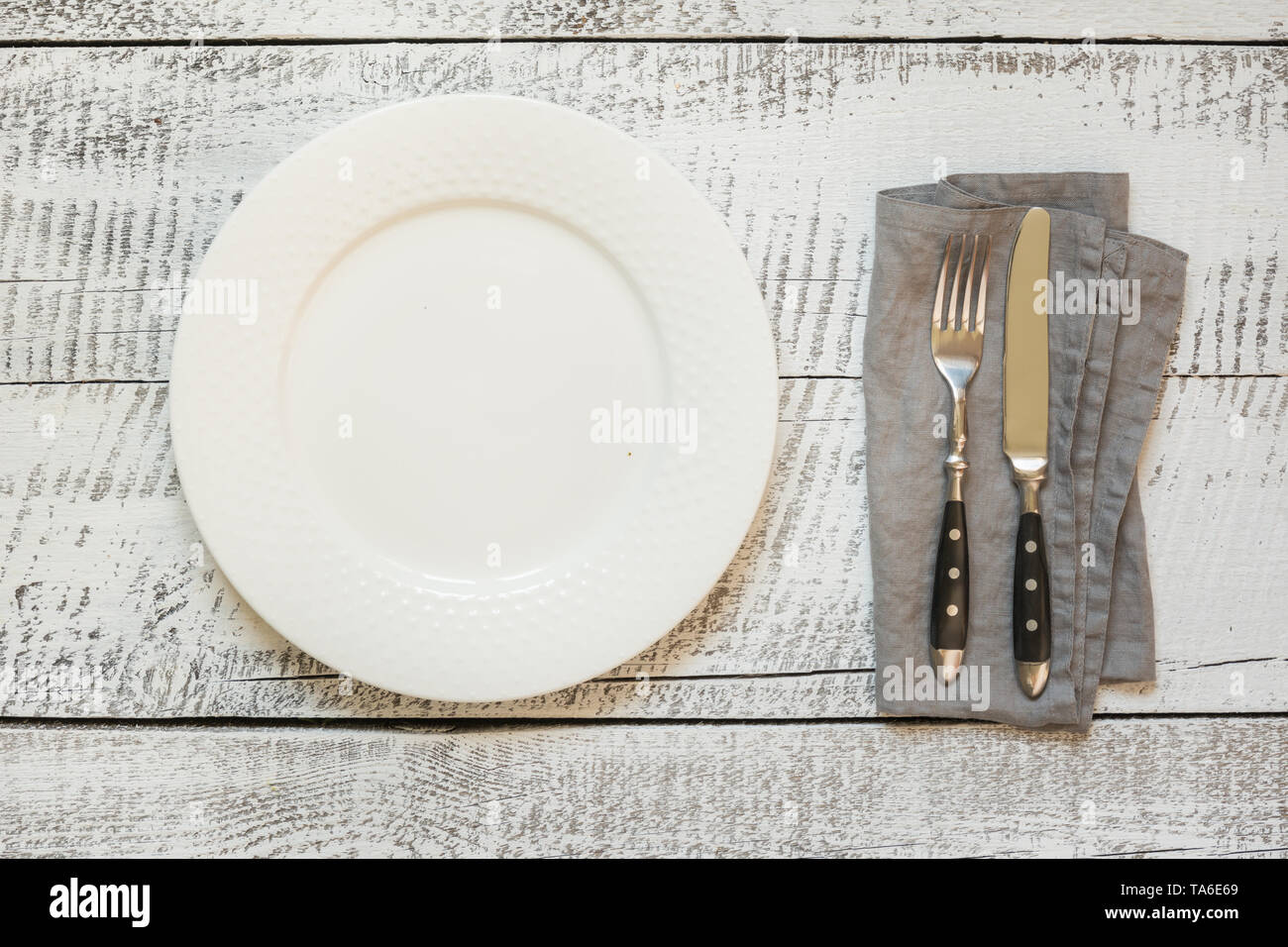 Elegante luogo tabella di impostazione con piastra bianca su vintage tavolo in legno. Visualizzare vrom sopra. Orientamento orizzontale. Foto Stock