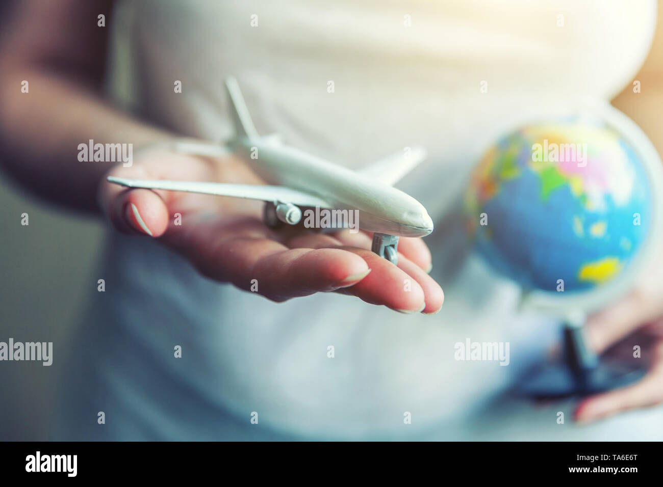Donna femmina mani piccoli toy piano modello e mappa del globo. Il viaggio in aereo week-end di vacanza viaggio avventura biglietto di viaggio tour consegna aerea Foto Stock