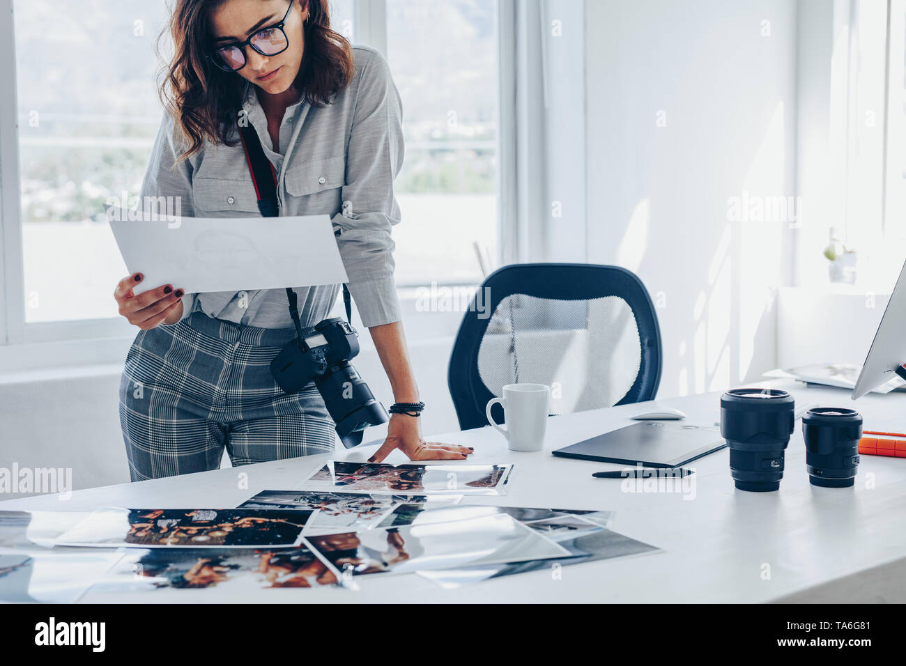 Giovane donna occupato a lavorare nel suo studio. Femmina caucasica fotografo stampe di controllo dopo lo sviluppo. Foto Stock