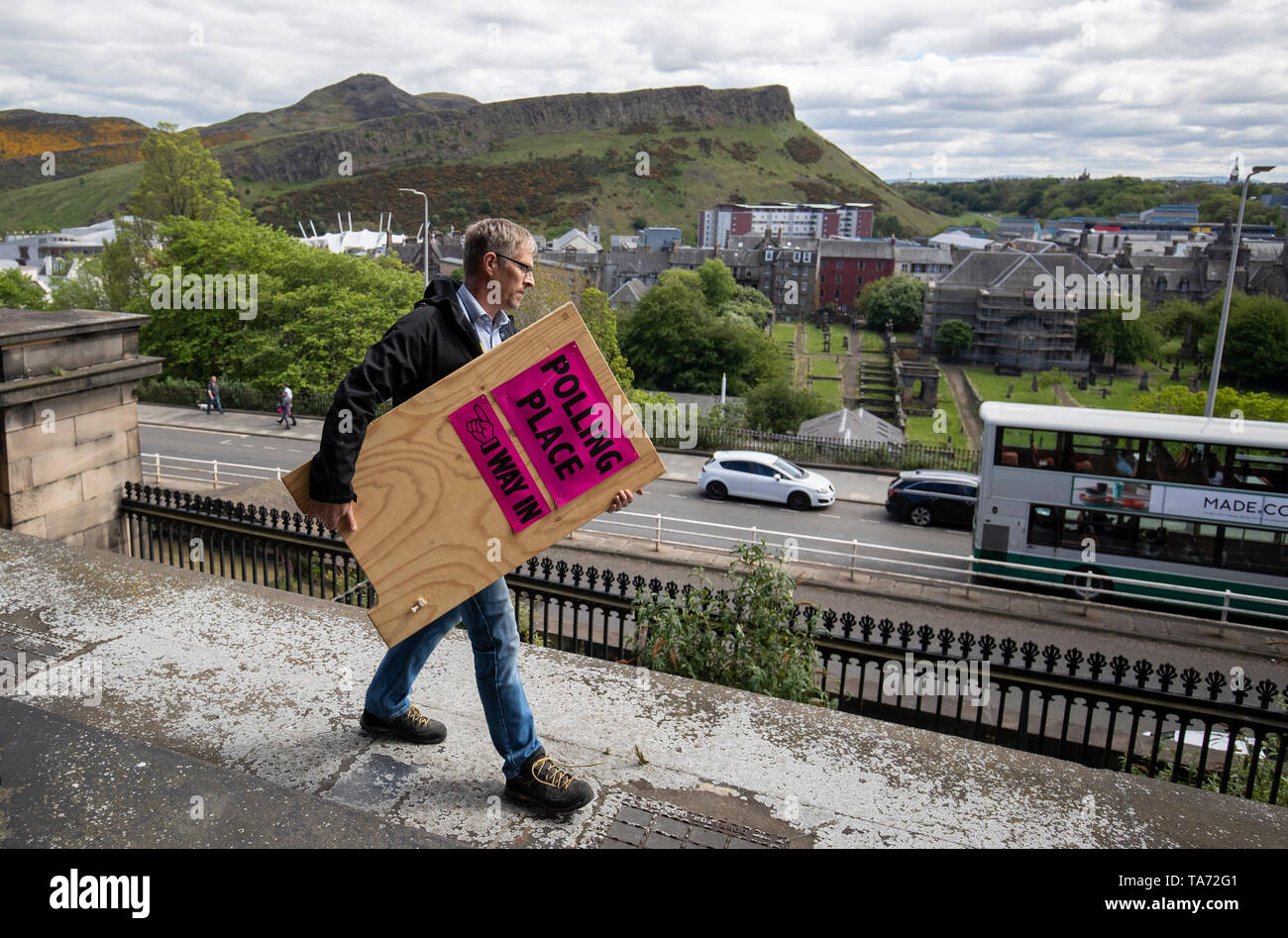 Elezione membro dello staff Scott Russell porta uno dei centinaia di stazione di polling segni di essere spedite al polling di stazioni in tutta la Scozia dal vecchio Royal High School, Edimburgo davanti al Parlamento elezioni politiche. Foto Stock