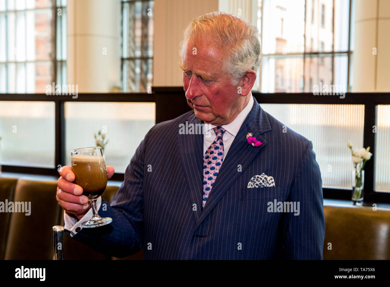 Il Principe di Galles ha un bicchiere di Belfast Black fatta da Whitewater birreria come frequenta un ricevimento presso il Grand Central Hotel ha ospitato dallo Spirito di Belfast per celebrare coloro coinvolti nella fornitura il successo del turismo e artigianale di settori alimentari a Belfast. Foto Stock