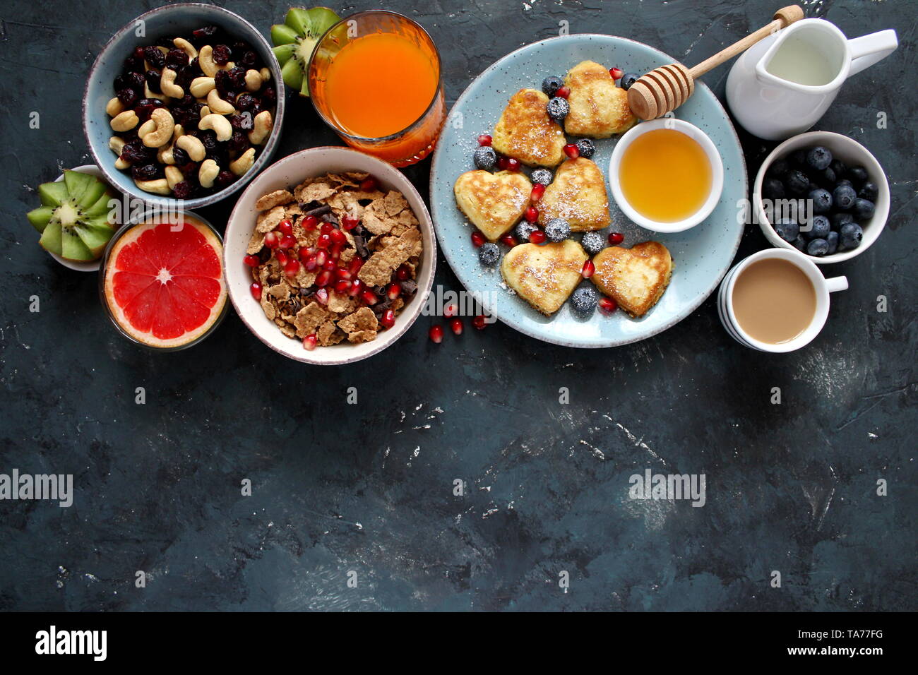 Il brunch o colazione concetto su sfondo scuro. Vista da sopra con copia spazio. Una sana prima colazione. Sana colazione pancake, frutta secca, caffè, granola. Foto Stock