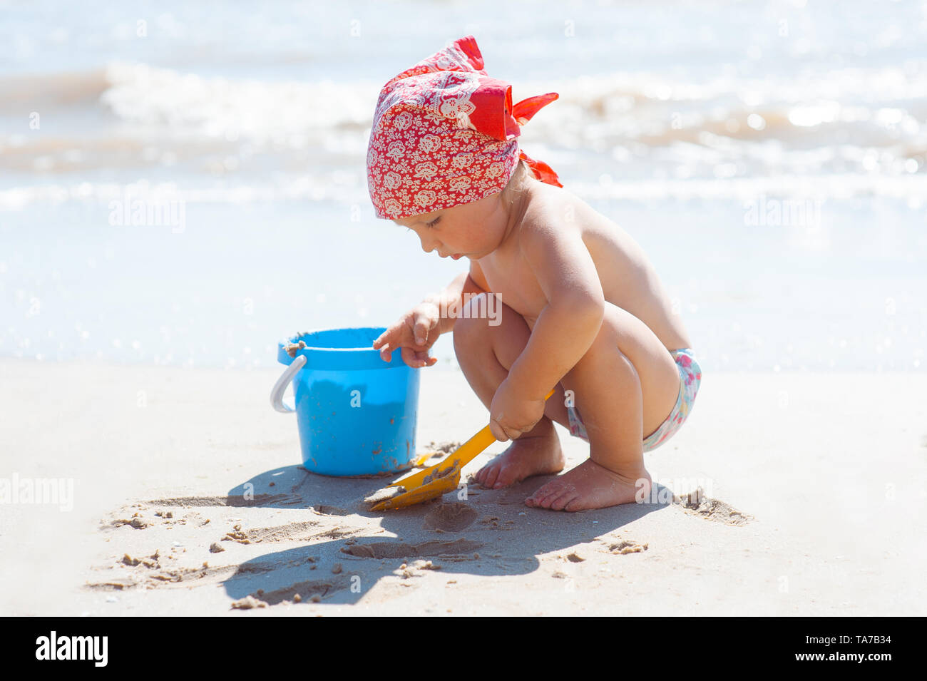 Ragazza di capretto gioca su una spiaggia. Bambino costruzione castello di sabbia sulla spiaggia. Divertimento estivo in acqua per la famiglia. Ragazza con secchi giocattolo e spade sulla riva del mare Foto Stock