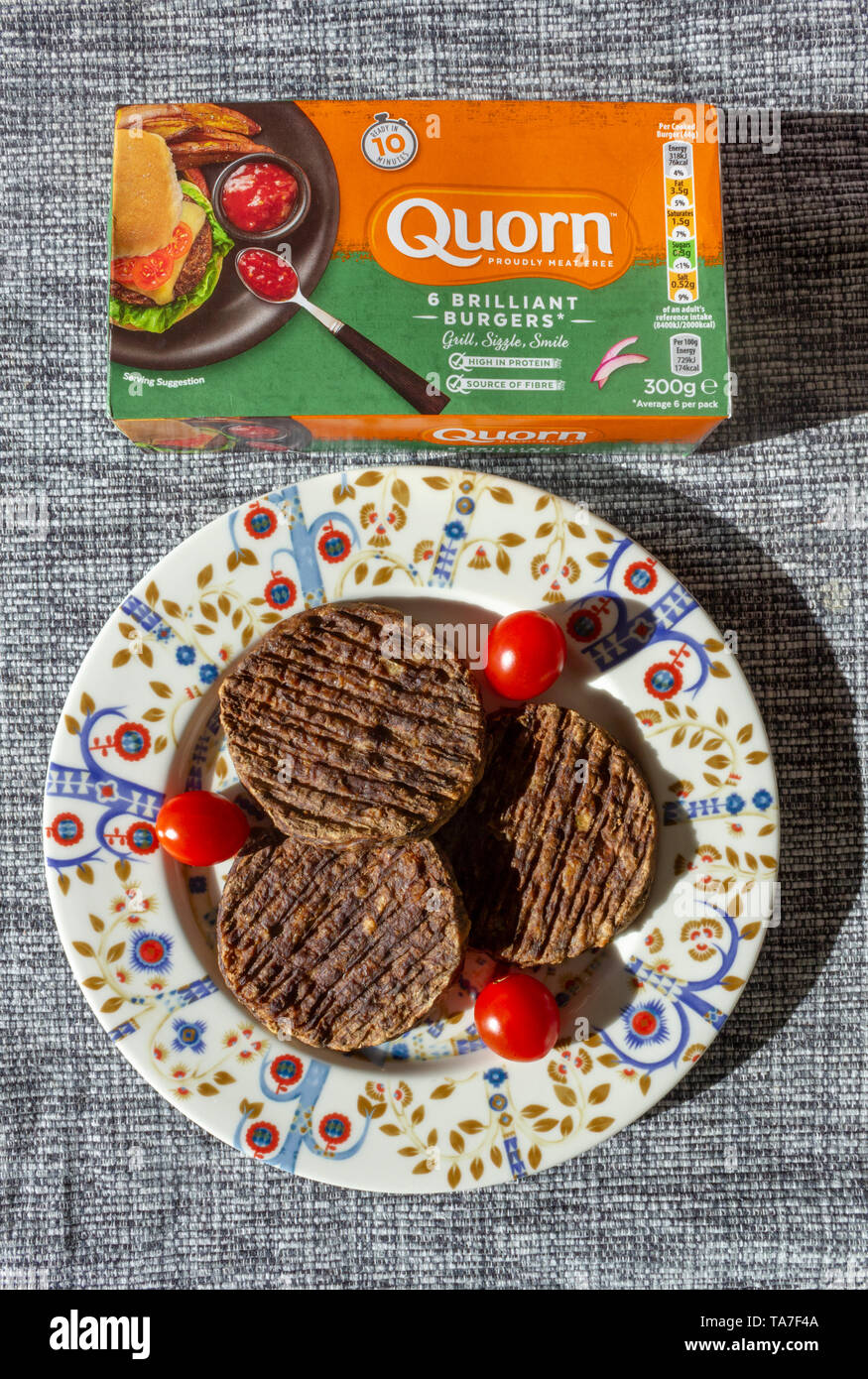 Carne vegetariani-free quorn burger e prugna tomoatoes su una colorata verticale della piastra Foto Stock