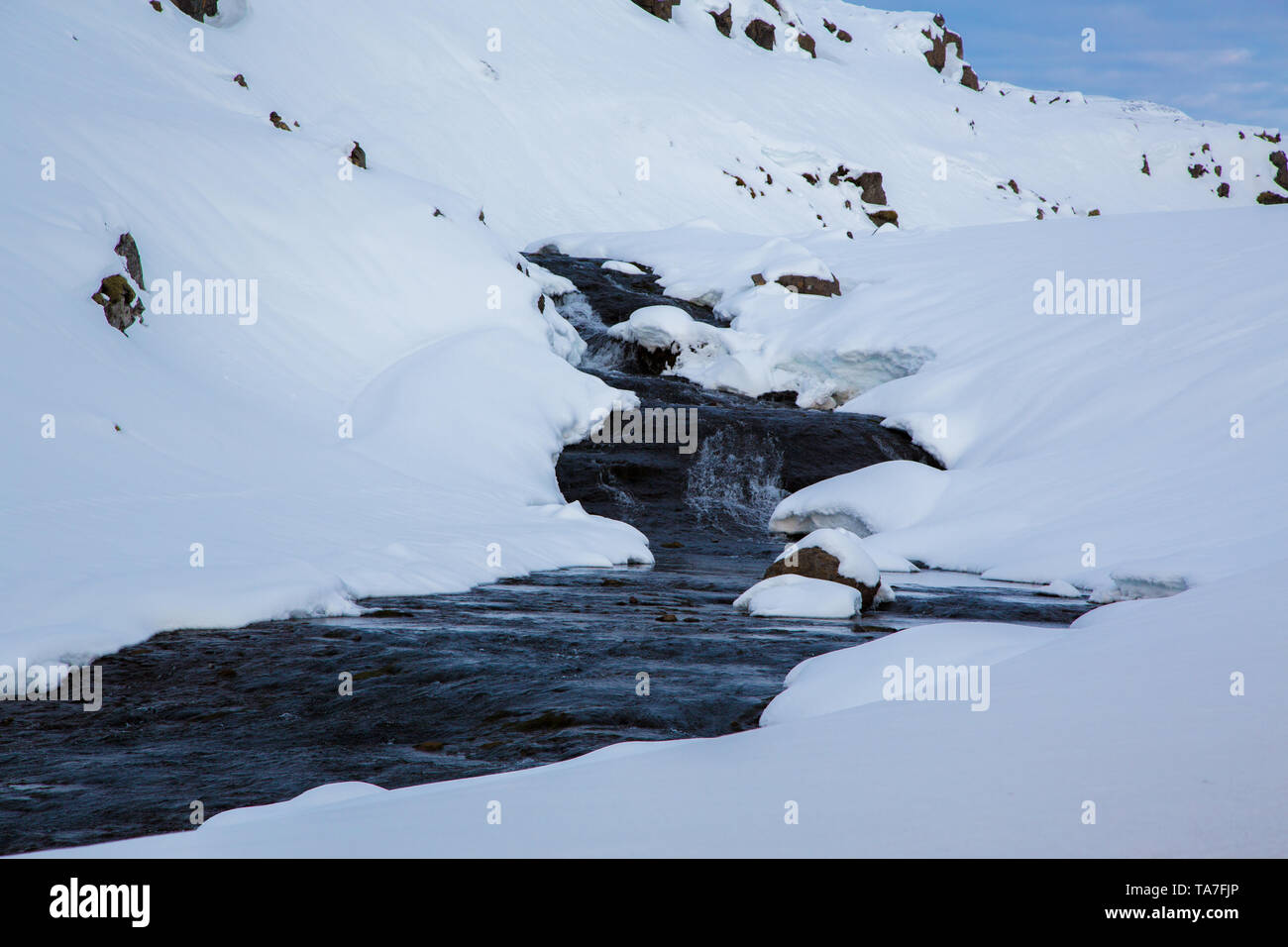 Creek si snoda attraverso la neve nelle Highlands di Islanda Foto Stock