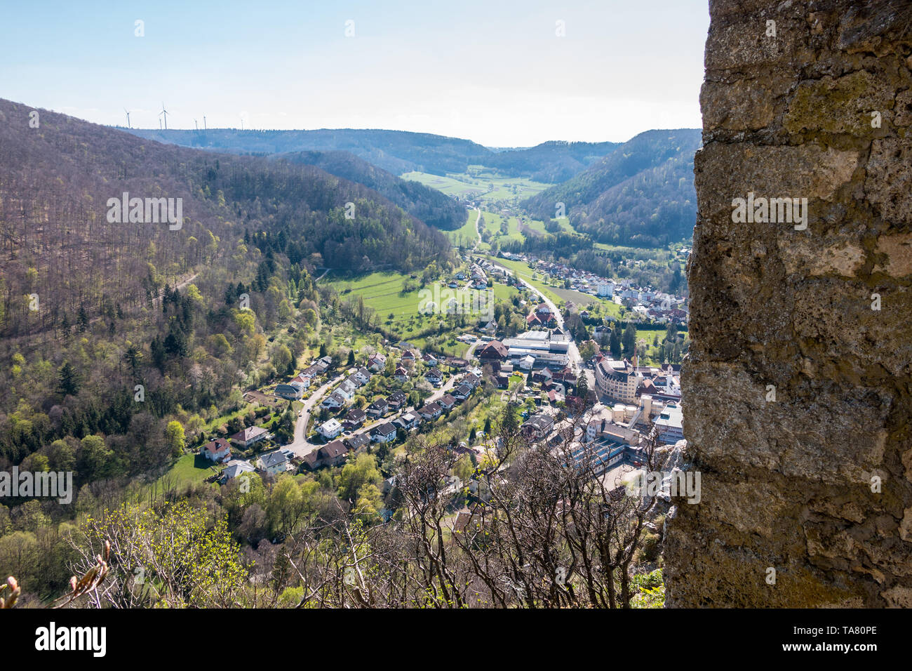 Piccolo villaggio nel mezzo della campagna tedesca con le colline, boschi, campi e prati e le mura di un castello Foto Stock