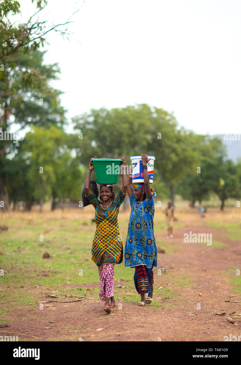 Peul tribù ragazze trasportare secchi pieni di acqua sulla testa, Savanes distretto, Boundiali, Costa d'Avorio Foto Stock