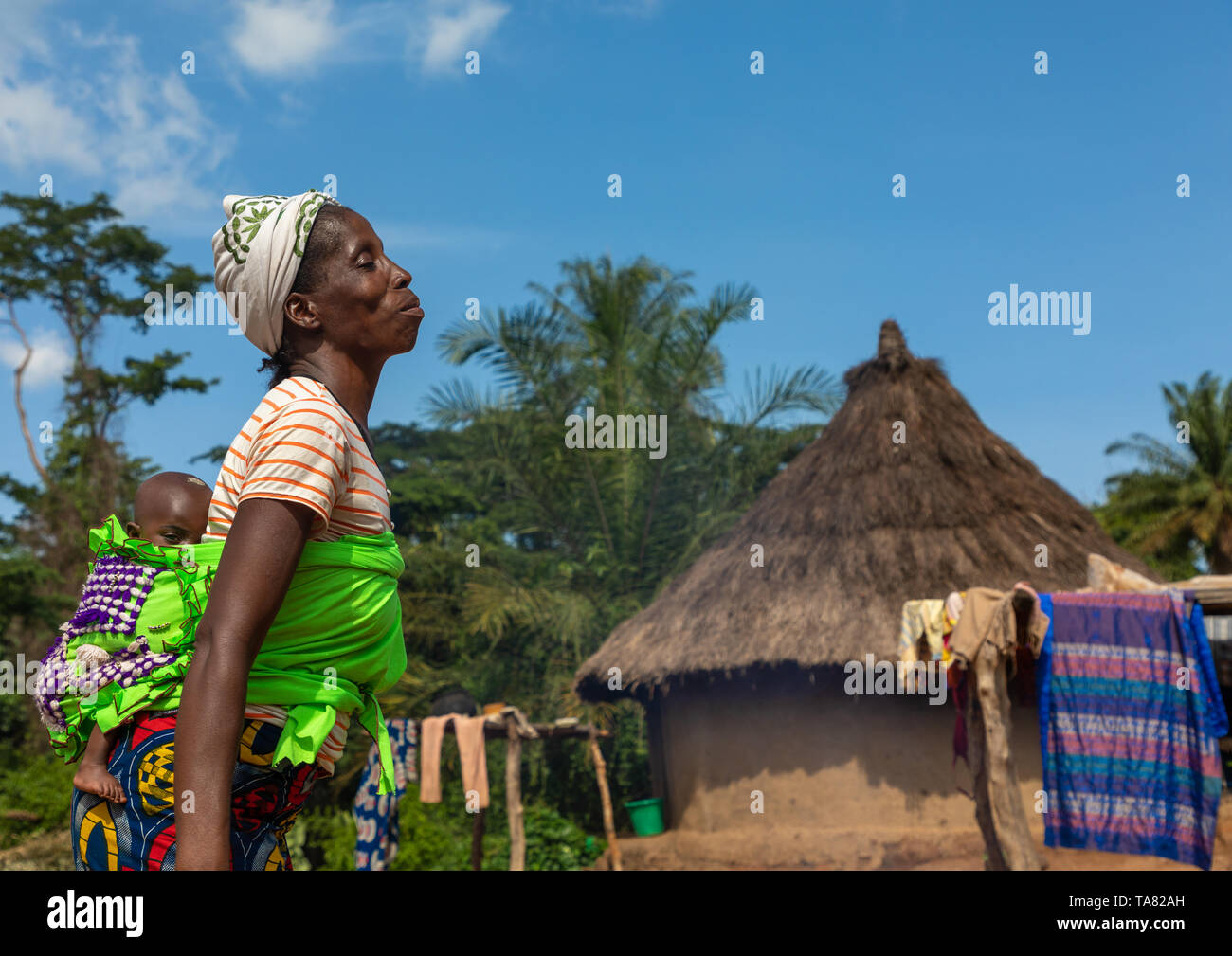 Madre africana che porta il suo bambino ragazza nel suo indietro, Bafing, Gboni, Costa d'Avorio Foto Stock