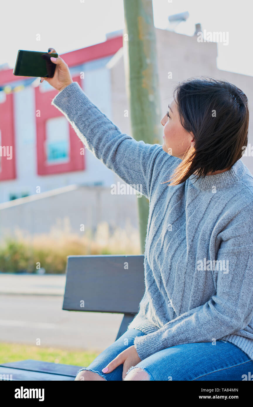 Ragazza giovane parlando su smartphone e digitare messaggi con lo smartphone Foto Stock