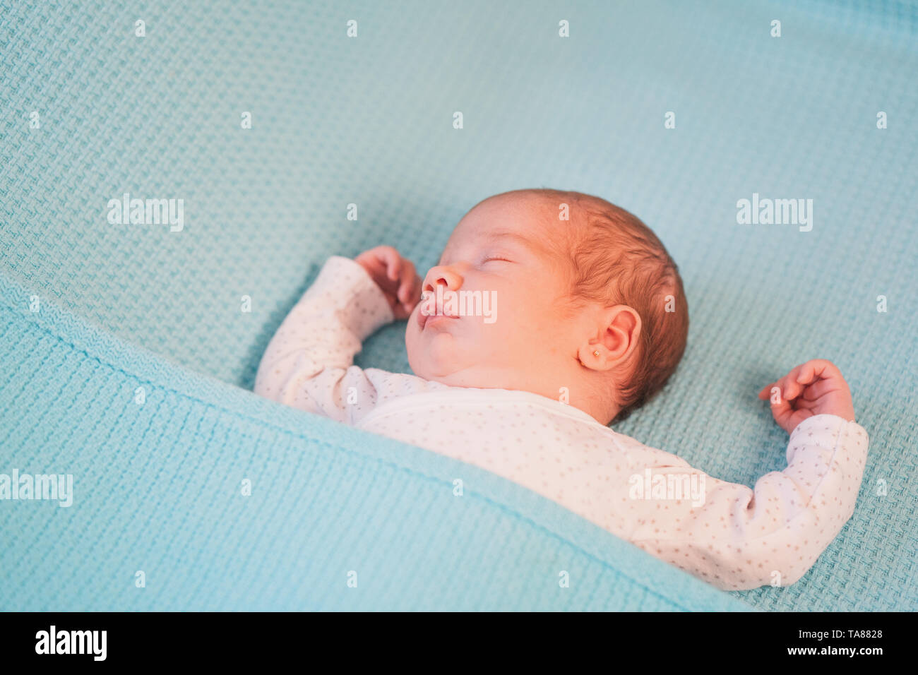 Poco carino bambino giacente a braccia aperte su un letto su fogli di blu. Sweet Dreams. Foto Stock