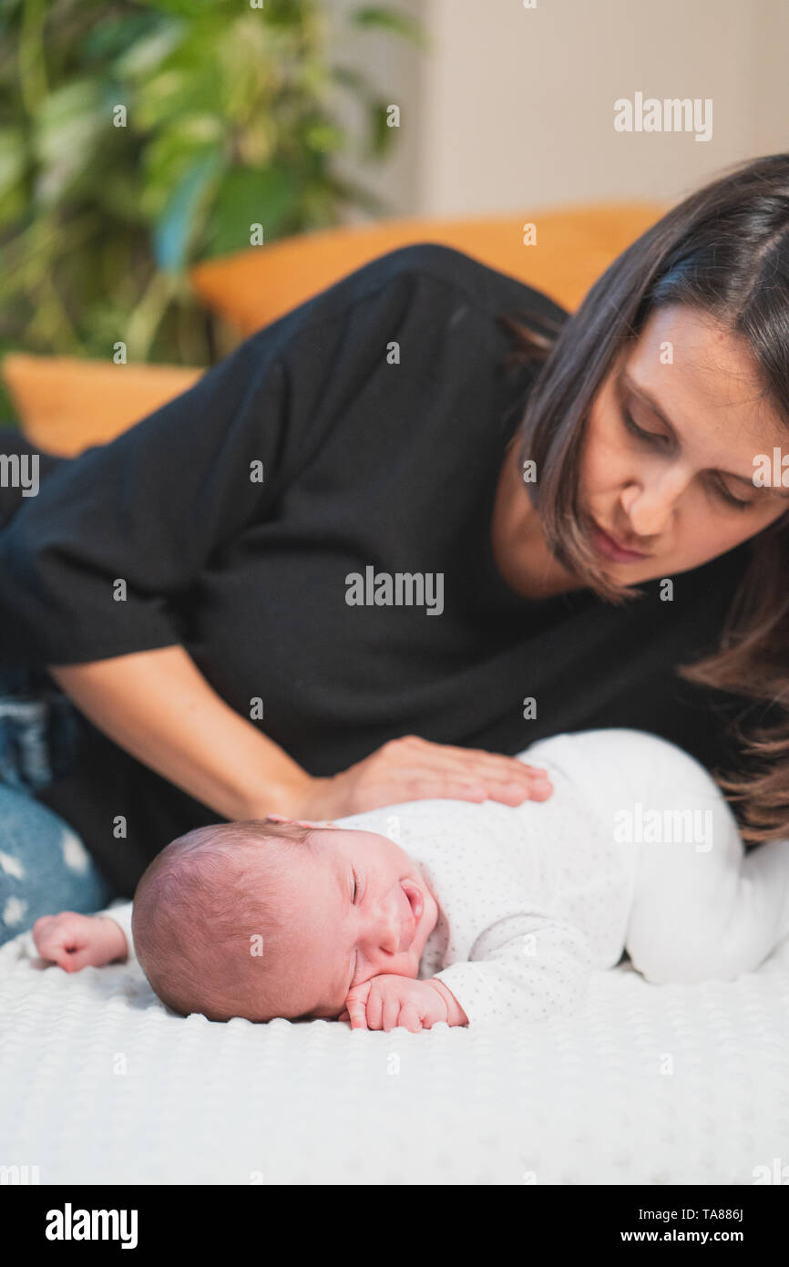 Felice madre dando coccole e giocare sorridente con il suo grazioso neonato. Famiglia, vita nuova, infanzia, inizio concetto. Foto Stock