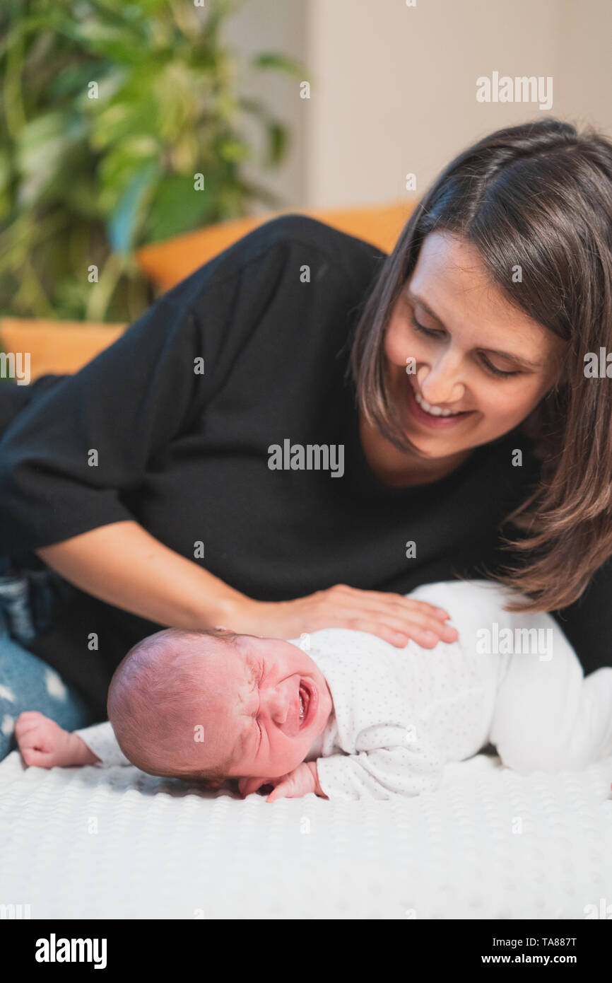 Felice madre dando coccole e giocare sorridente con il suo grazioso neonato. Famiglia, vita nuova, infanzia, inizio concetto. Foto Stock