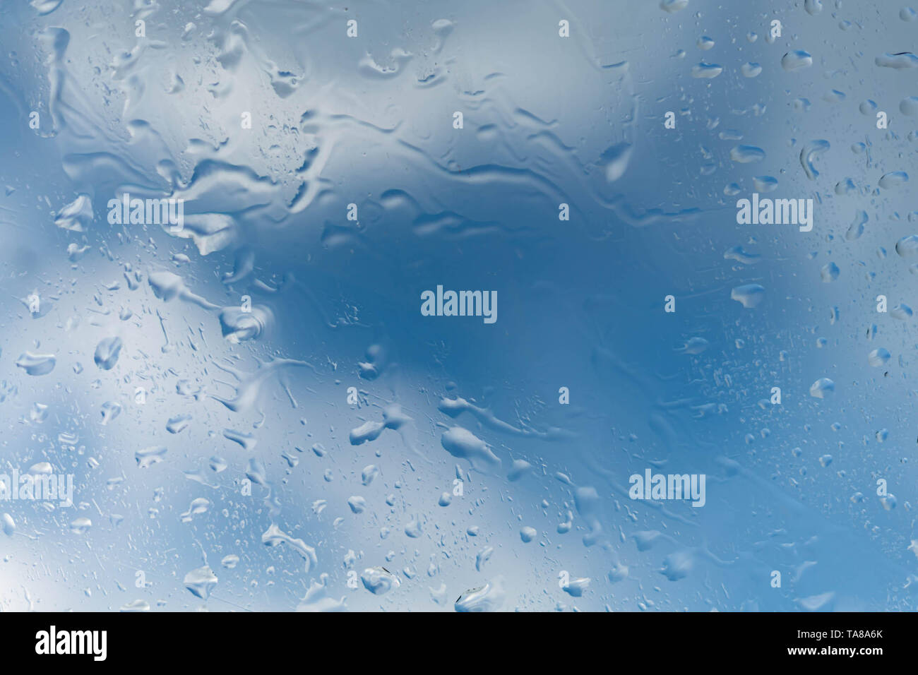 Gocce di pioggia su una finestra un cielo blu di una nuvola. Foto Stock