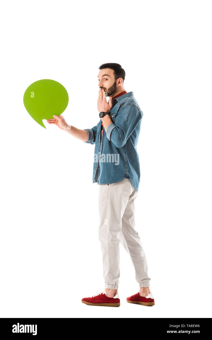 Sorpreso uomo bello con bolle di pensiero tenendo la mano vicino alla bocca isolato su bianco Foto Stock