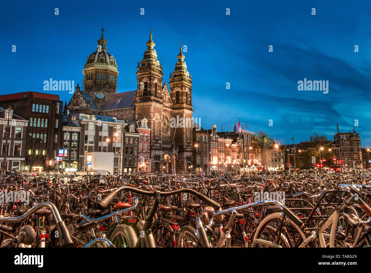 Amsterdam biciclette - biciclette ad Amsterdam di notte con la Chiesa di San Nicola in background - centinaia di biciclette parcheggiate - biketown Amsterdam Foto Stock
