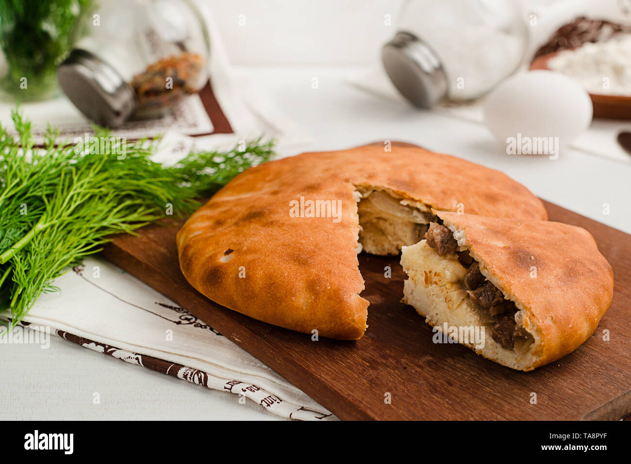 Salate russo tradizionale torta con carne e aneto. Mostra gli ingredienti. Home cottura degli alimenti fotografia in toni caldi. Foto Stock