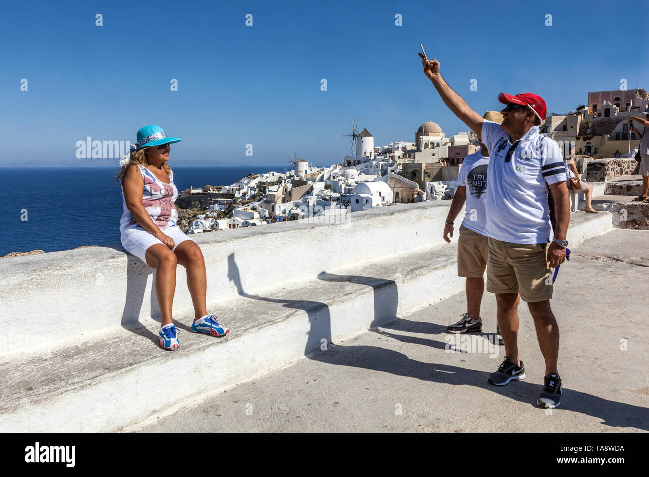 Santorini Oia, turisti anziani sulla terrazza, le persone sul famoso punto di vista scattare foto su cellulare, isole greche, Grecia in viaggio per l'Europa Foto Stock