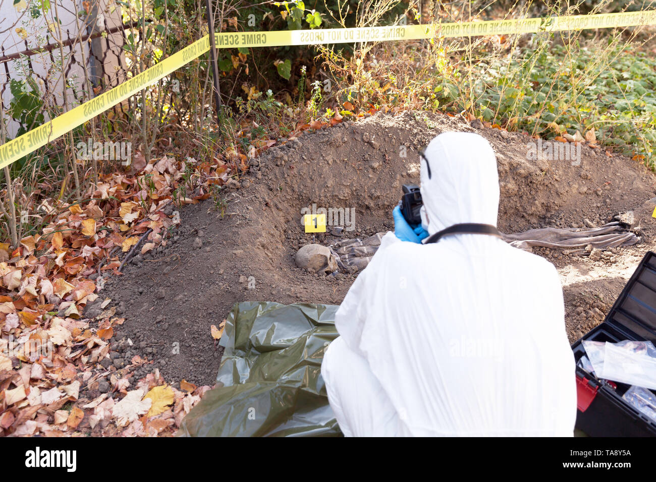 Le scienze forensi specialista in bianco workwear scattare foto del cordoned fuori scena del crimine Foto Stock