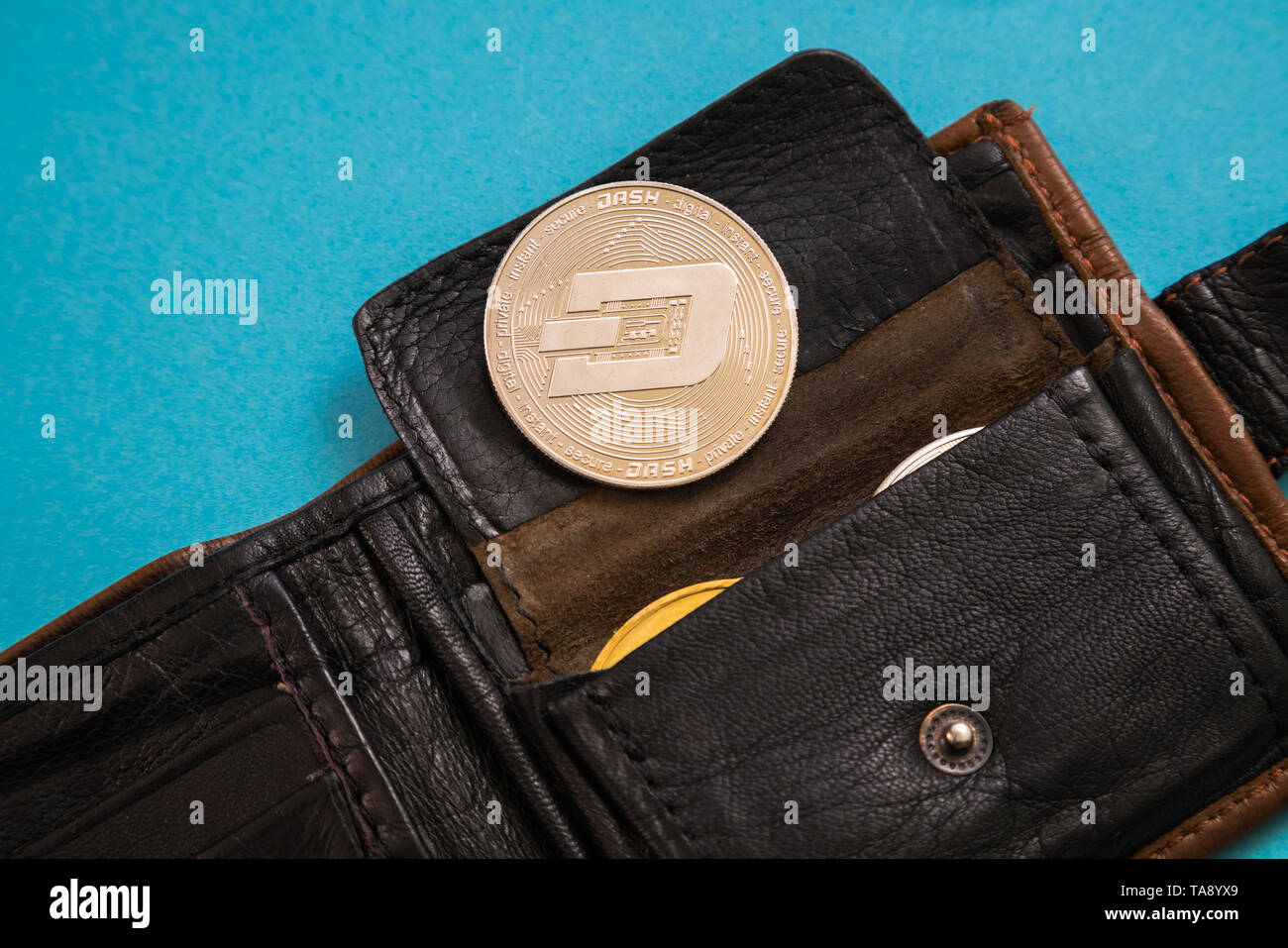 Coin Dash grippaggio al di fuori del portafoglio in pelle o sfondo blu. Valuta digitale, catena di blocco di mercato. Foto Stock
