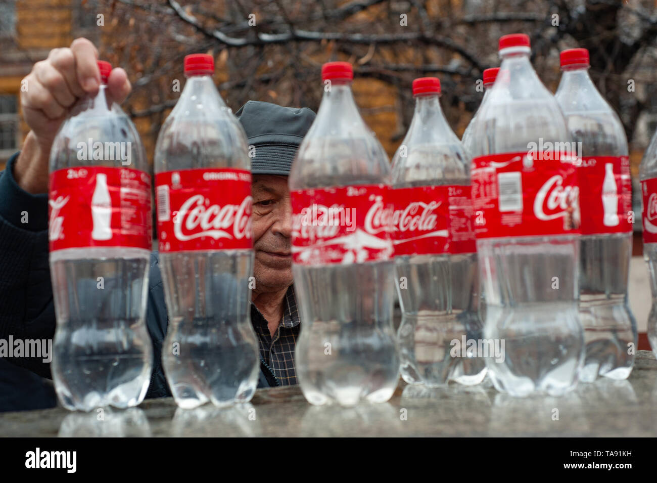 Un vecchio uomo bulgaro il riempimento di bottiglie di Coca Cola con acqua minerale a una primavera calda nel centro o di Sofia, Bulgaria Foto Stock