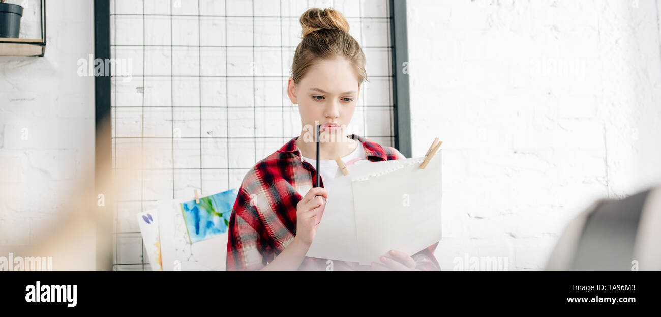 Panoramica di concentrato di adolescente tenendo pen e carte Foto Stock