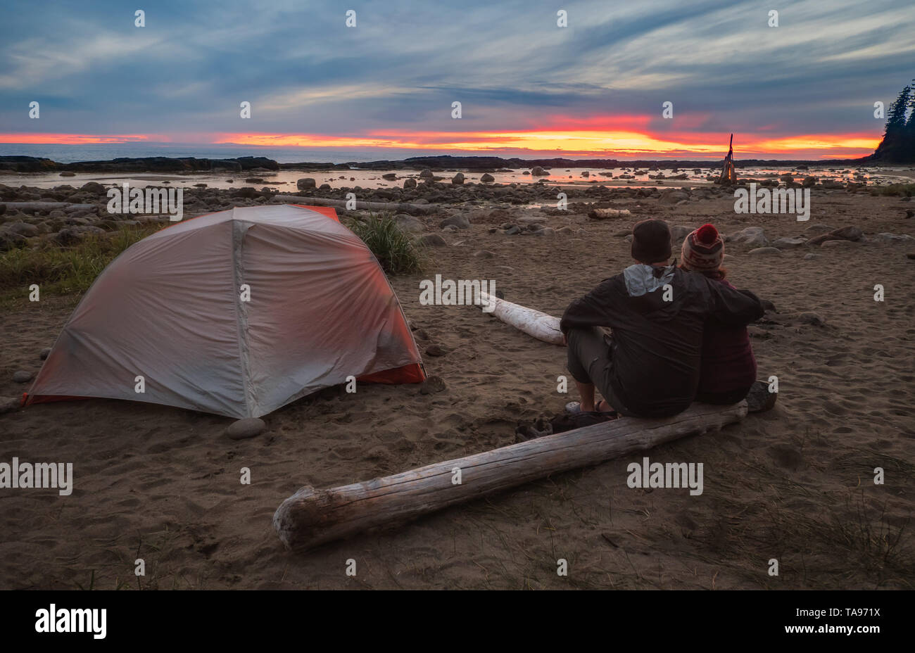 Due persone godendo di un tramonto a un campeggio dopo una lunga giornata di escursioni la West Coast Trail sull'Isola di Vancouver, British Columbia, Canada. Foto Stock