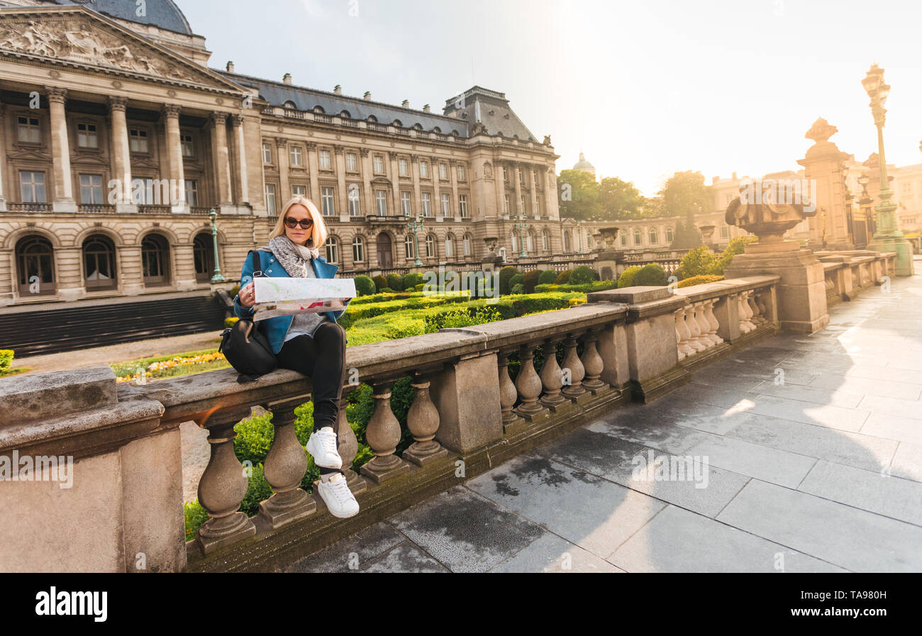 Ragazza seduta con una mappa sullo sfondo del Palazzo Reale di Bruxelles in Belgio Foto Stock