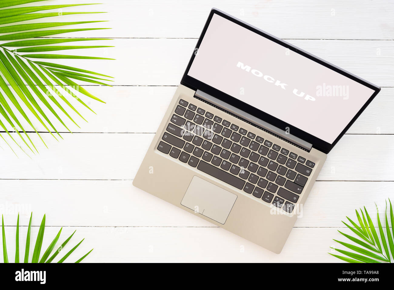 Mock up display del computer portatile su bianco tavolo in legno per vacanze estive il concetto di sfondo. Appartamento laici vista superiore del Notebook portatile tropicale e foglie di palmo w Foto Stock