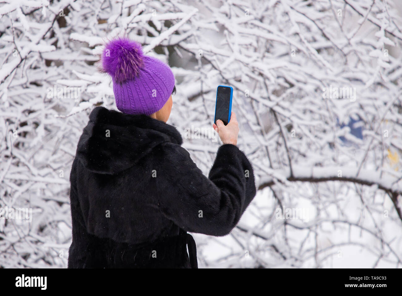 Donna di scattare una foto del paesaggio invernale vista con un telefono cellulare. Foto Stock