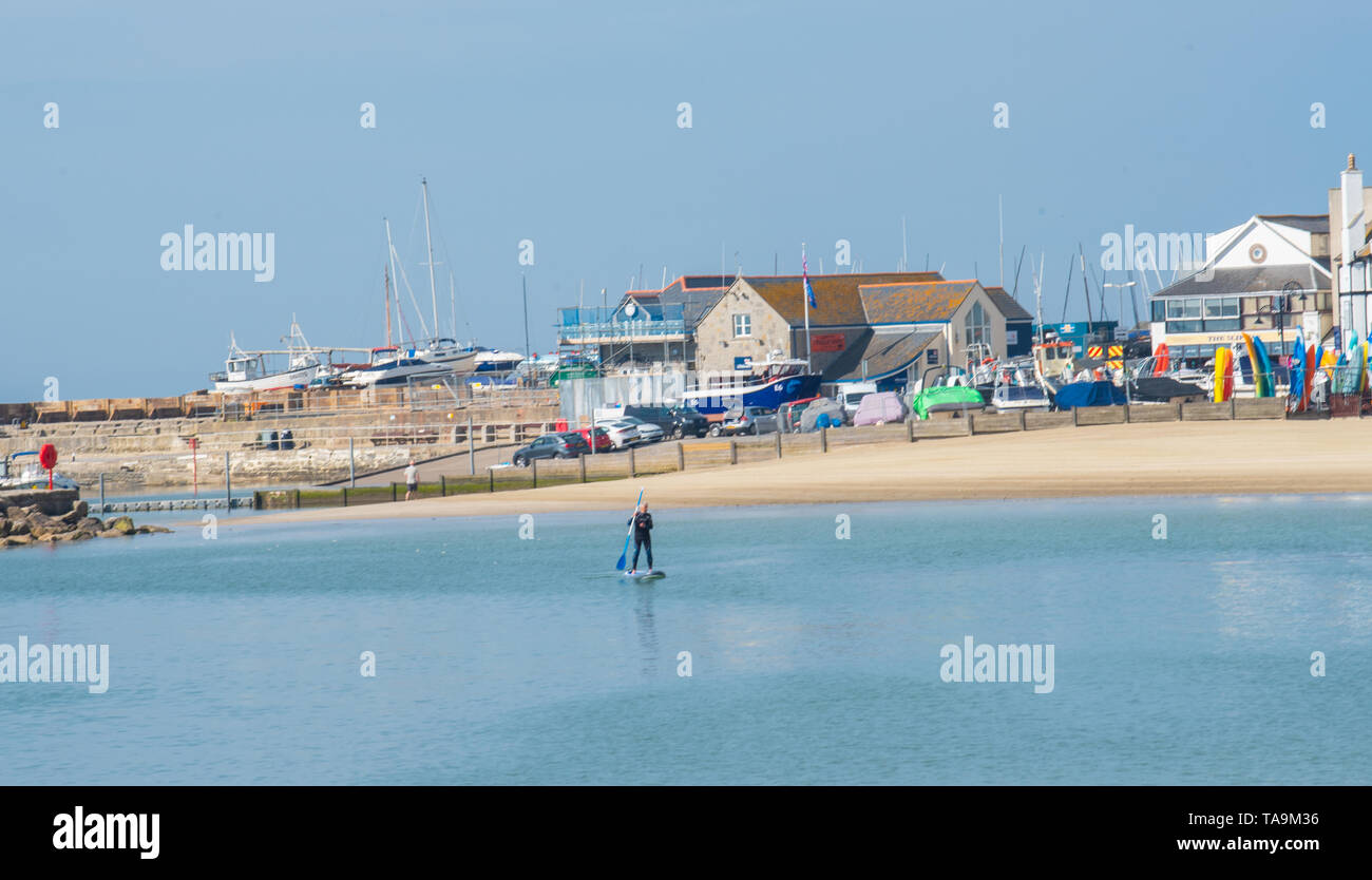 Lyme Regis, Dorset, Regno Unito. Il 23 maggio 2019. Regno Unito: Meteo una gloriosa mattina presso la pittoresca spiaggia della località balneare di Lyme Regis. Il popolare resort è calmo e tranquillo oggi in vista delle prossime vacanze di maggio. Un lone paddle boarder sfrutta le condizioni pacifiche. Folle di visitatori sono attesi al gregge per la famosa spiaggia di La prossima settimana a crogiolarvi nel mite clima che è stato meteo di tutta la costa sud dell'Inghilterra. Credito: Celia McMahon/Alamy Live News. Foto Stock