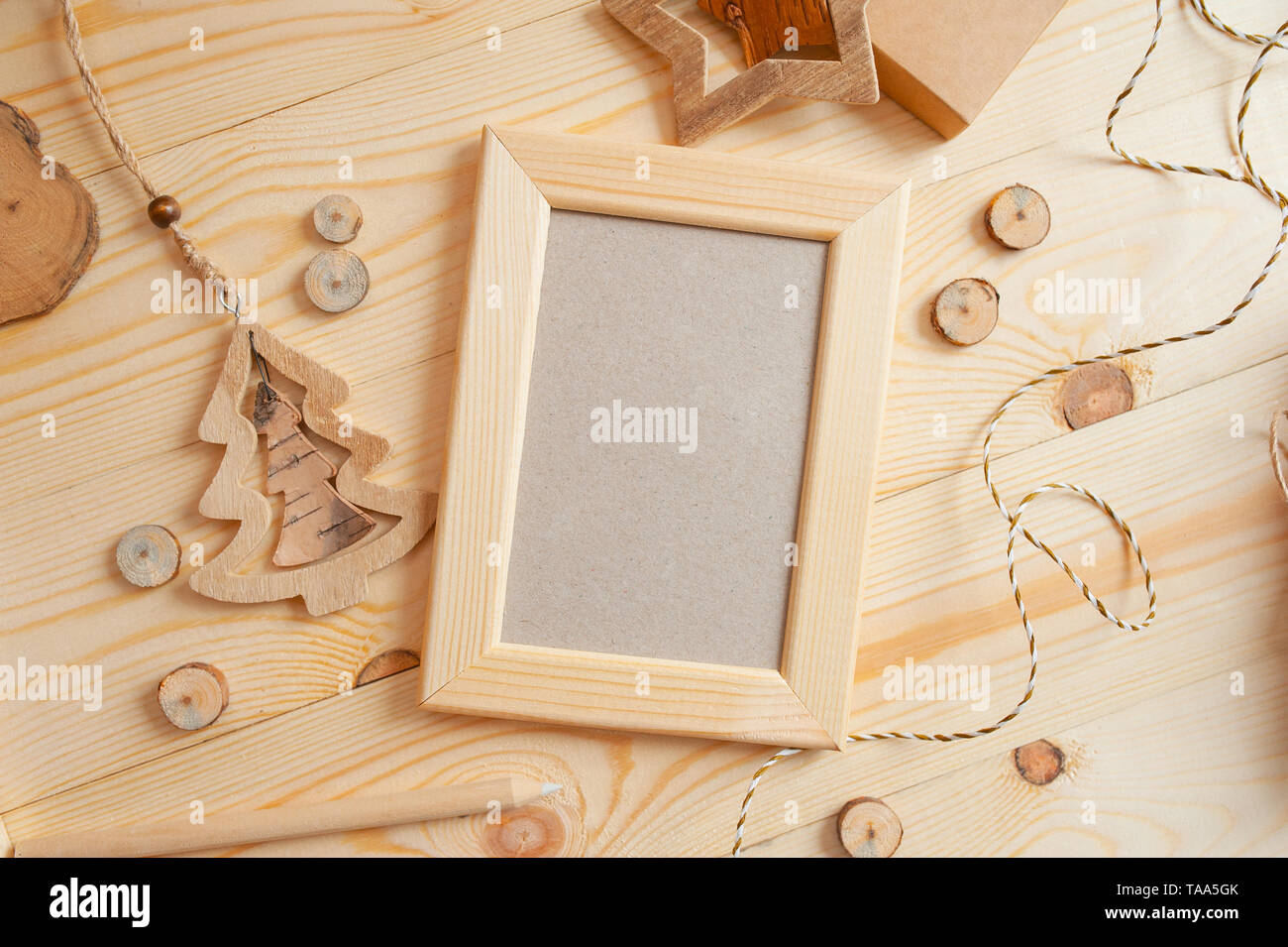 Cornice di legno chiaro di Natale per foto su sfondo di legno con corda e giocattoli di legno. Mockup di foto con vista dall'alto e disposizione piatta Foto Stock