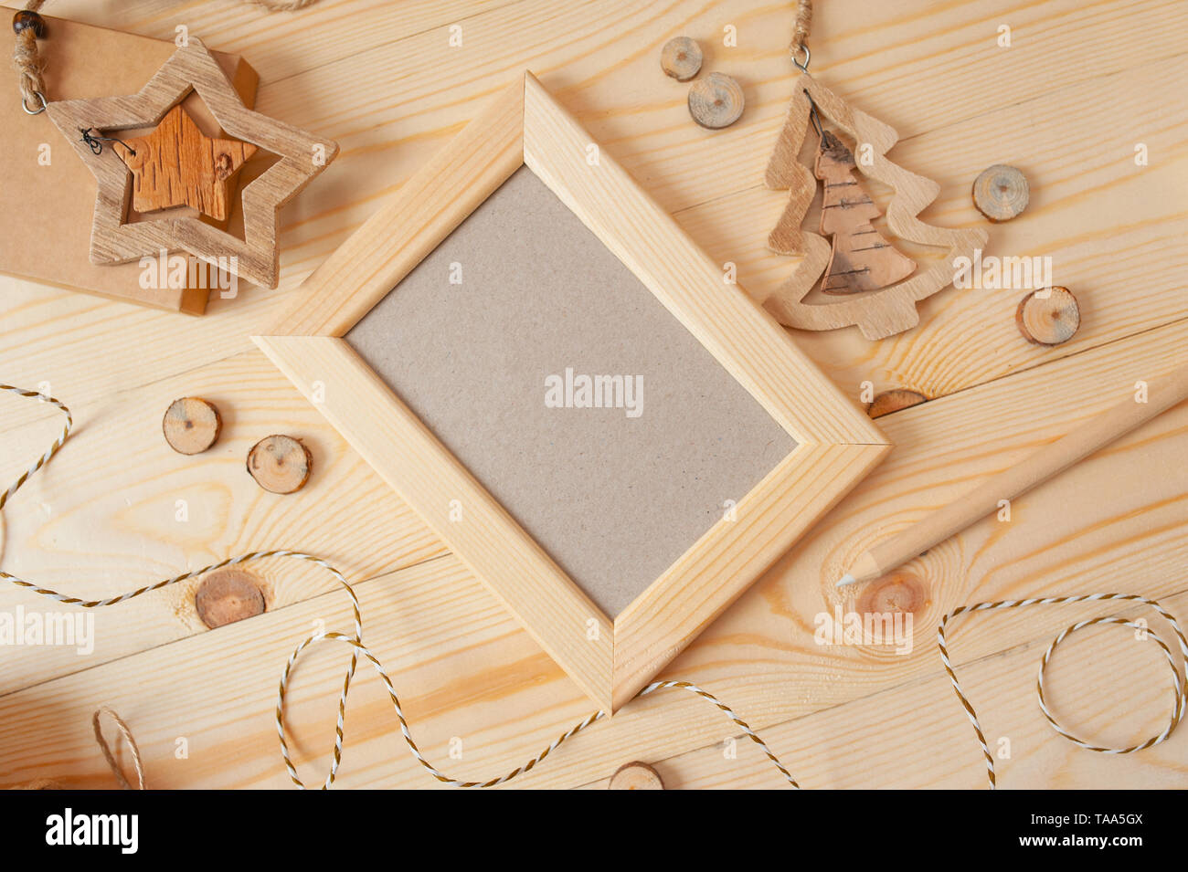 Cornice di legno chiaro di Natale per foto su sfondo di legno con corda e giocattoli di legno. Mockup di foto con vista dall'alto e disposizione piatta Foto Stock