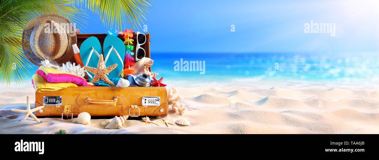 Valigetta completa con accessori sulla spiaggia tropicale Foto Stock