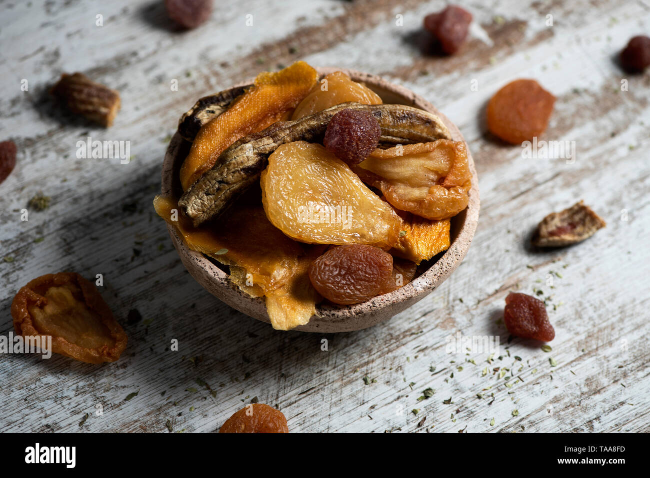 Primo piano di un rustico vaso di terracotta pieno di assortimento di frutta secca, come pera, pesca, banana, fragola, Apple o di albicocca, su un bianco di legno rustico Foto Stock