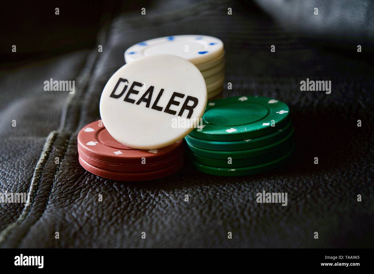 Il Poker e il concessionario Chips su una texture di sfondo in pelle Foto Stock