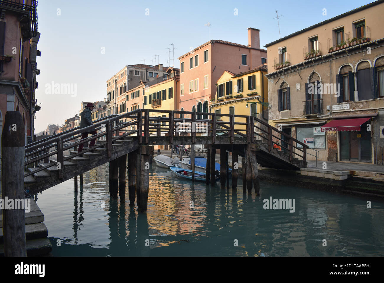 Un uomo a piedi attraverso un ponte di legno a Venezia. Foto Stock