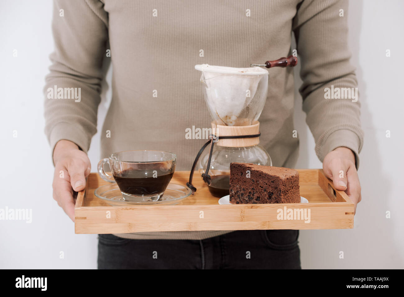 Caffè di gocciolamento sul vassoio in legno con torta al cioccolato. Tempo di caffè sul cafe con luce naturale Foto Stock
