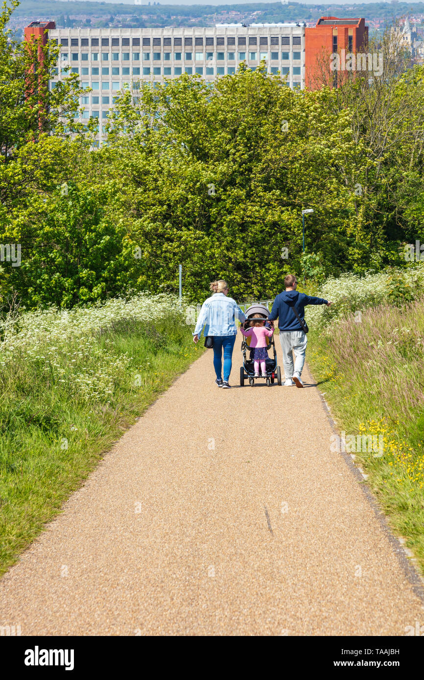 Una famiglia giovane con un bambino in un passeggino e una piccola ragazza in piedi sul retro a piedi da linee di Gillingham park verso Chatham, Kent, Regno Unito Foto Stock