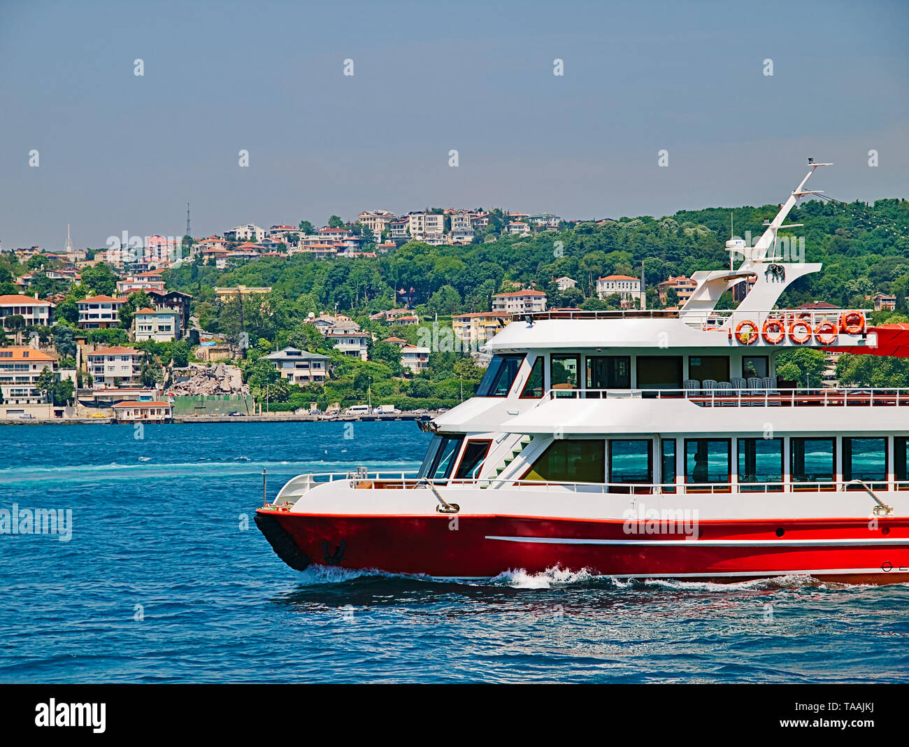 Piccolo rosso turistico la nave di crociera con n. di passeggeri al Bosforo stretto e edilizia residenziale a costa. Foto Stock