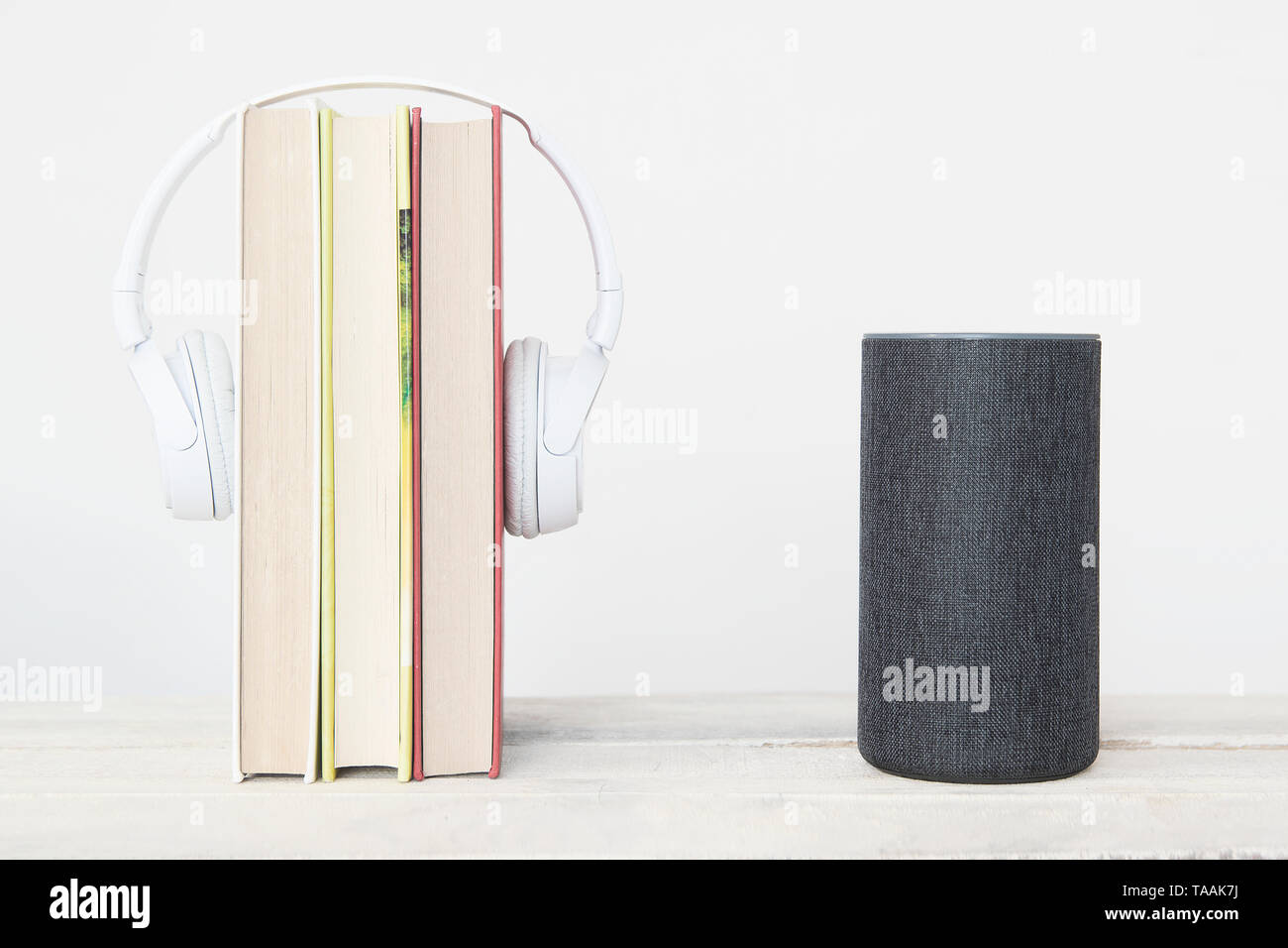 Smart speaker Amazon Alexa Echo dispositivo accanto ad alcuni libri e hearphones contro uno sfondo bianco. Svuotare lo spazio di copia per l'editor di testo Foto Stock