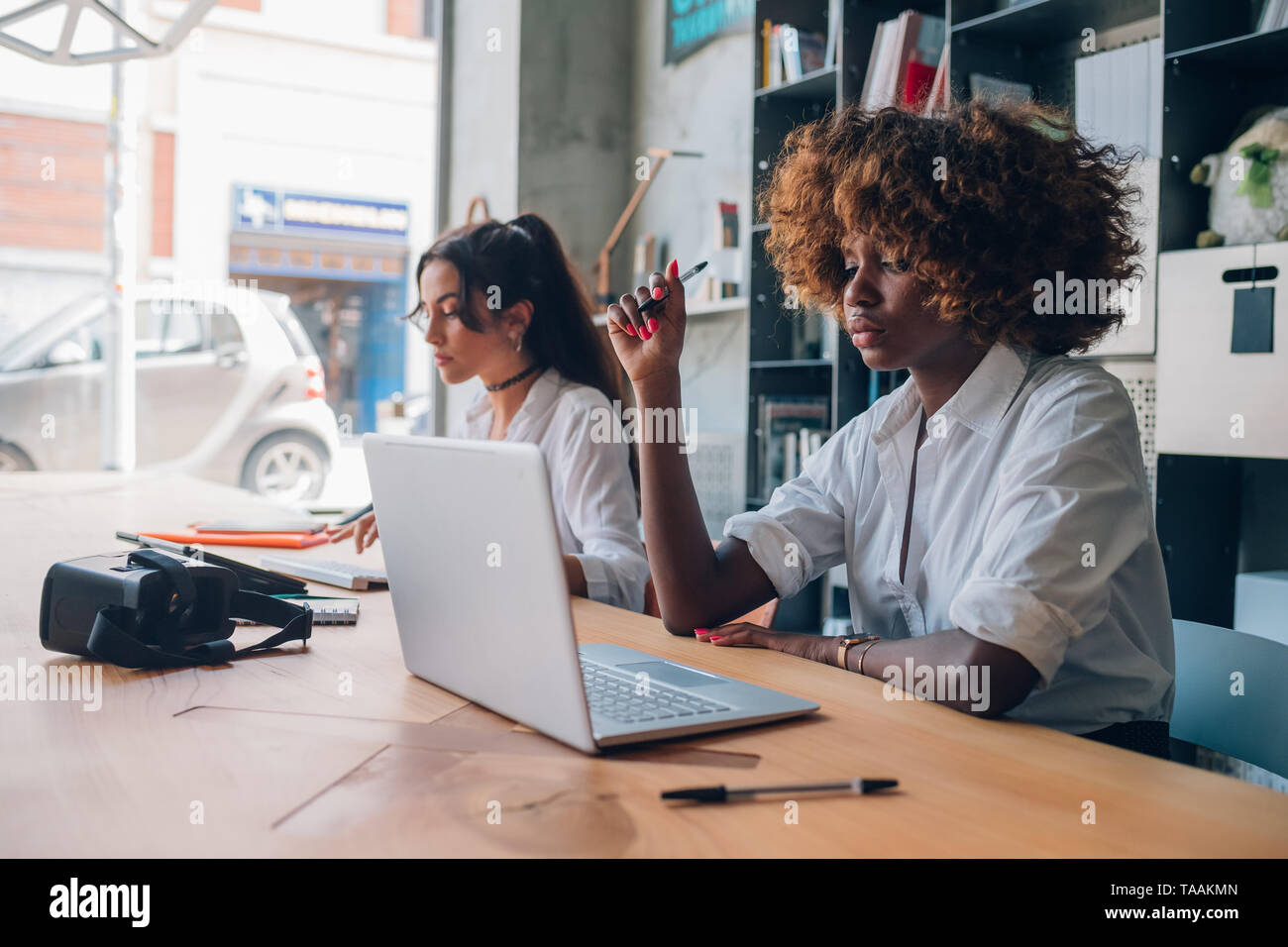 Due giovani donne e multirazziale lavorando su un progetto in un ufficio coworking, cooperazione - web design, creatività Foto Stock