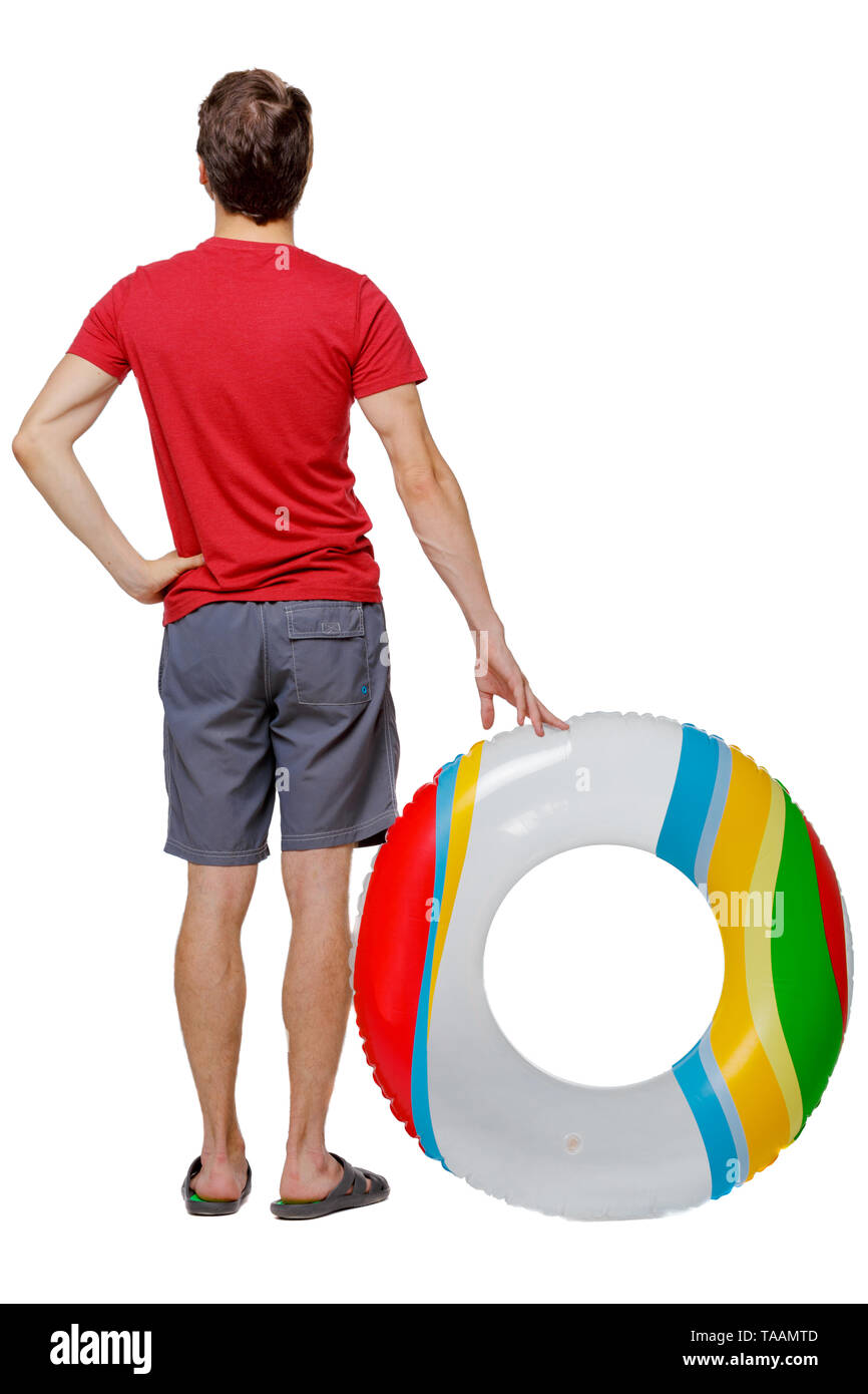 Vista posteriore di un uomo in pantaloncini corti con un cerchio gonfiabile. Il ragazzo sulla spiaggia. Vista posteriore di raccolta persone. vista posteriore di persona. Isolate su whi Foto Stock