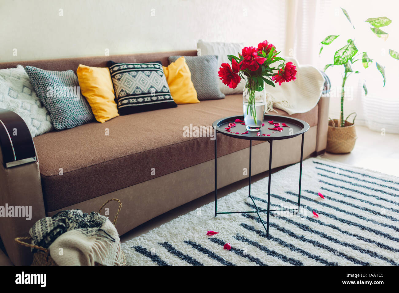 Interno della sala decorata con le peonie fiori, piante e tappeti. Accogliente lettino con cuscini e tavolo Foto Stock