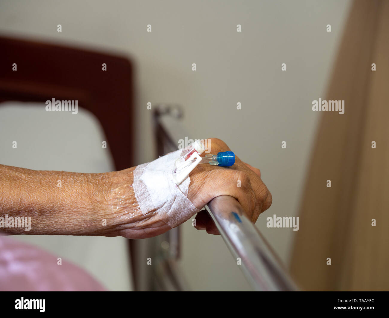 Chiudere fino a mano anziani paziente man mano con soluzione salina per via intravenosa (IV) di soluzione in ospedale. paziente con il tappo dell'ago per uso con la medicina per la soluzione salina Foto Stock